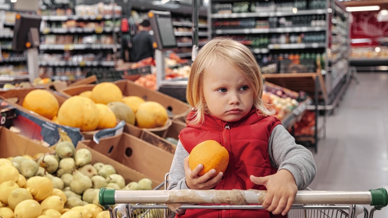 moeder in de supermarkt - boos kind in supermarktwagentje