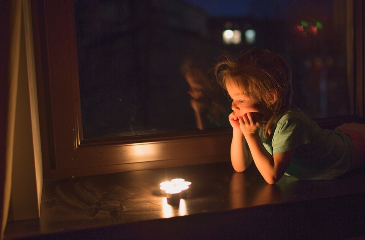 wereldlichtjesdag - kind kijkt in het donker naar kaarsje