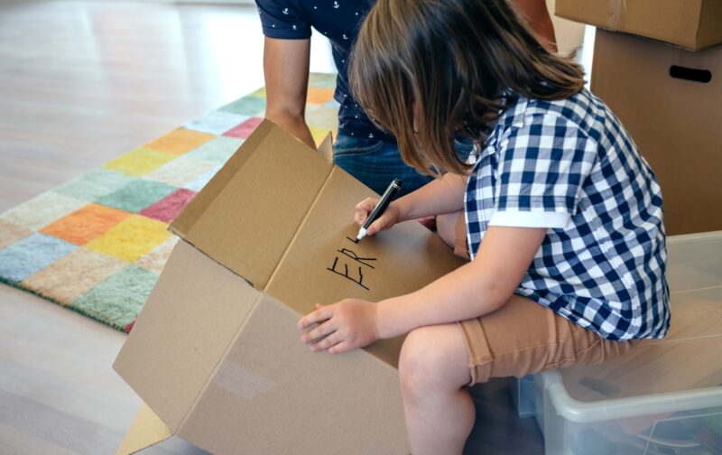 Kind schrijft zijn naam op een doos