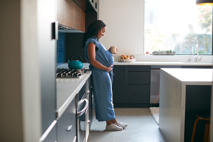 tips voor je met zwangerschapsverlof gaat 9 maanden zwanger vrouw in de keuken met kop thee