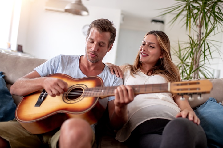 16 weken zwanger zwangere vrouw met man op de bank speelt gitaar