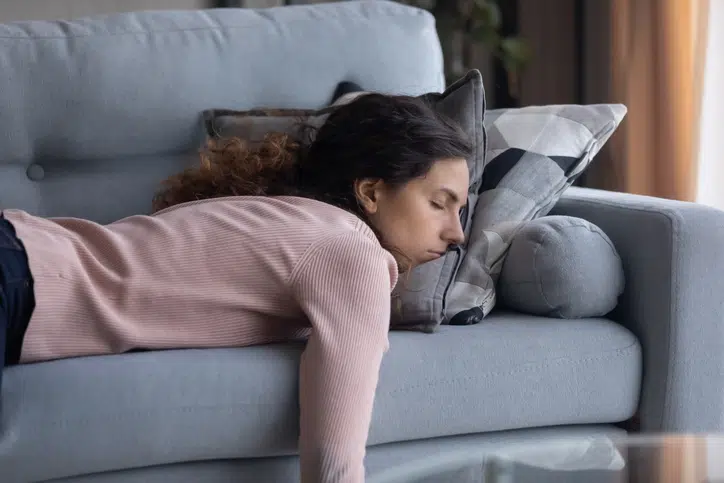 2 weken zwanger vrouw vermoeid op de bank