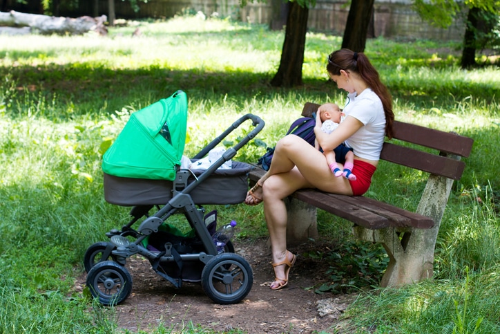 borstvoeding in het openbaar - jonge vrouw op een bankje in het park voedt haar baby