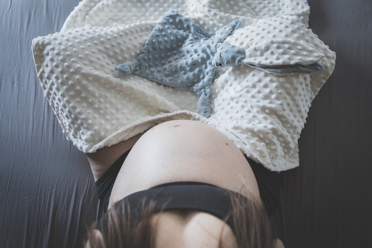 hoogzwangere vrouw in kleermakerszit met knuffel op schoot - natuurlijke bevalling