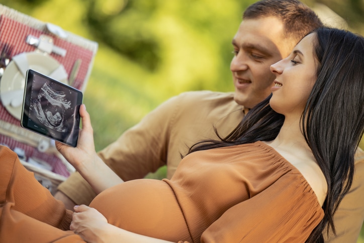 partner tijdens de bevalling - man en zwangere vrouw bekijken echofoto op tablet