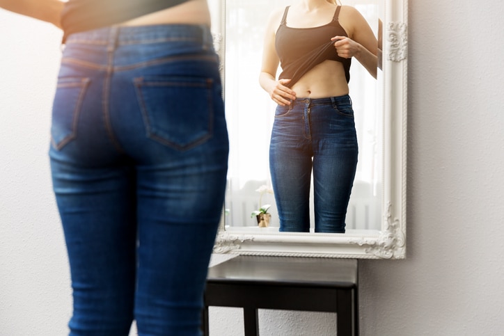 ontzwangeren vrouw bekijkt zichzelf in spiegel