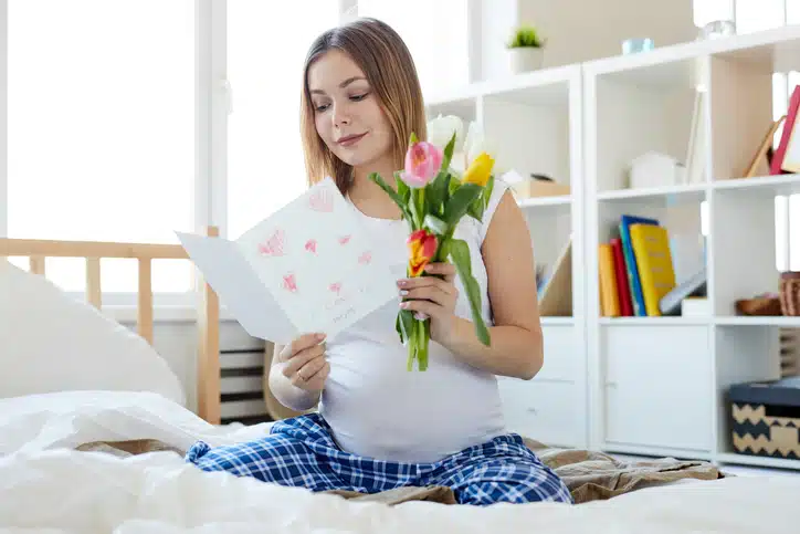eerste moederdag - zwangere vrouw met bos tulpen en kaart met hartjes