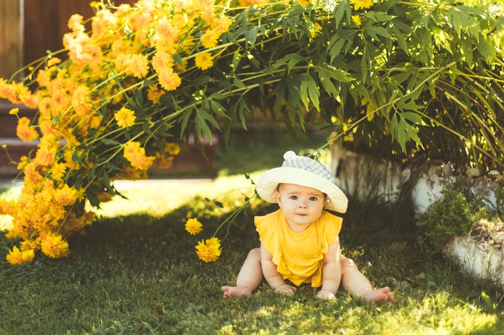 babyjurkjes - baby in een tuin met geel babyjurkje