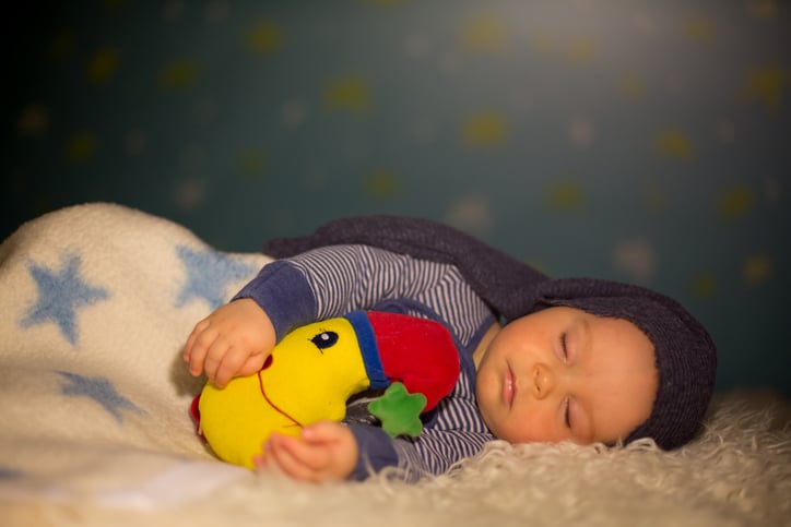 babyhoroscoop boogschutter slapende baby met knuffel in kamer met sterrenbehang