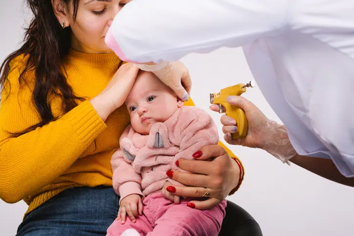 baby zit op schoot bij moeder - oorbellen schieten bij een baby