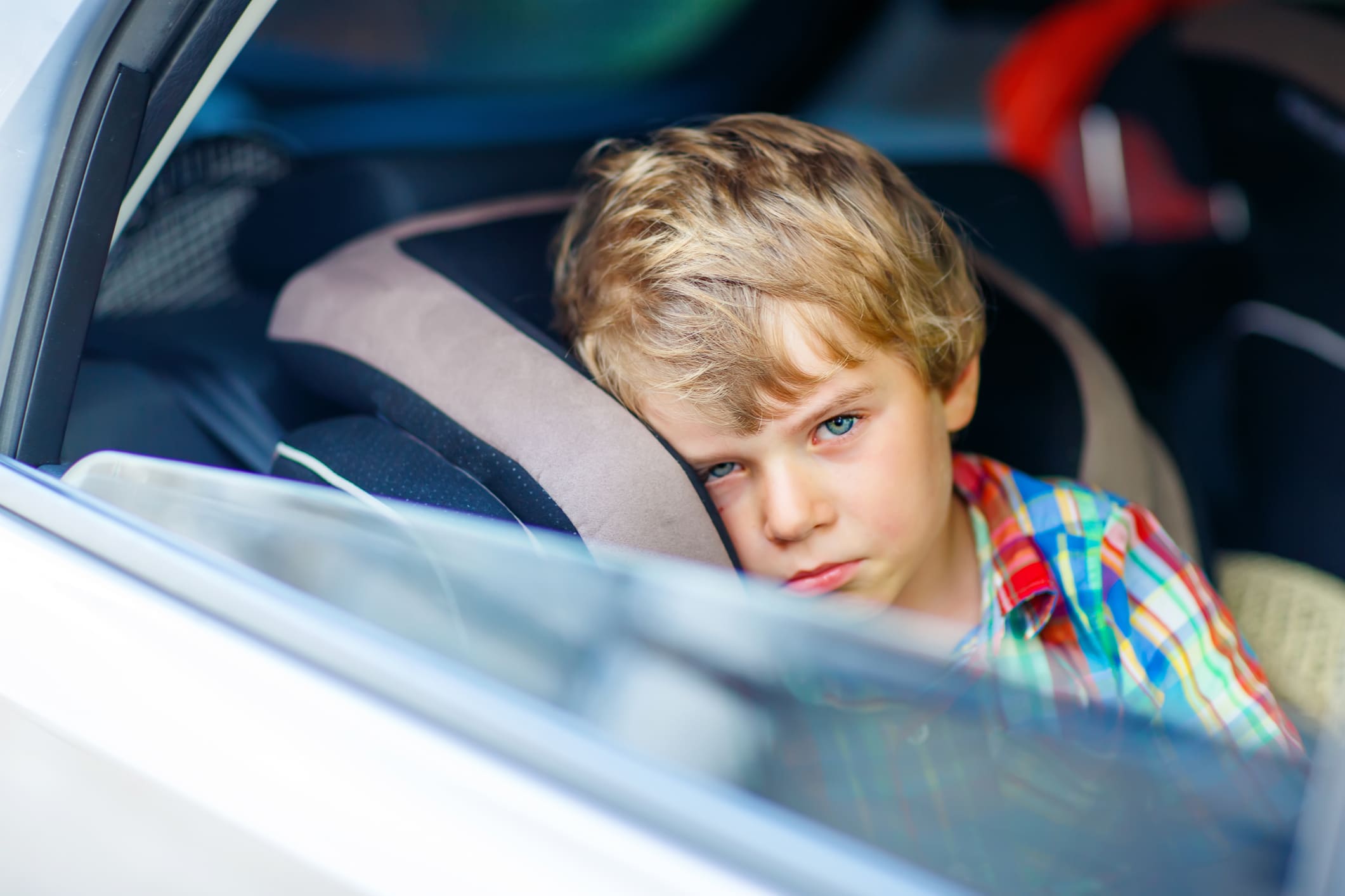 kind ziek op vakantie - jongen in auto kijkt sip uit het raam
