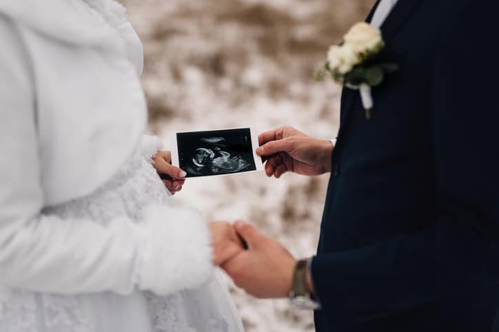 trouwen tijdens je zwangerschap - bruid en bruidegom houden echofoto vast