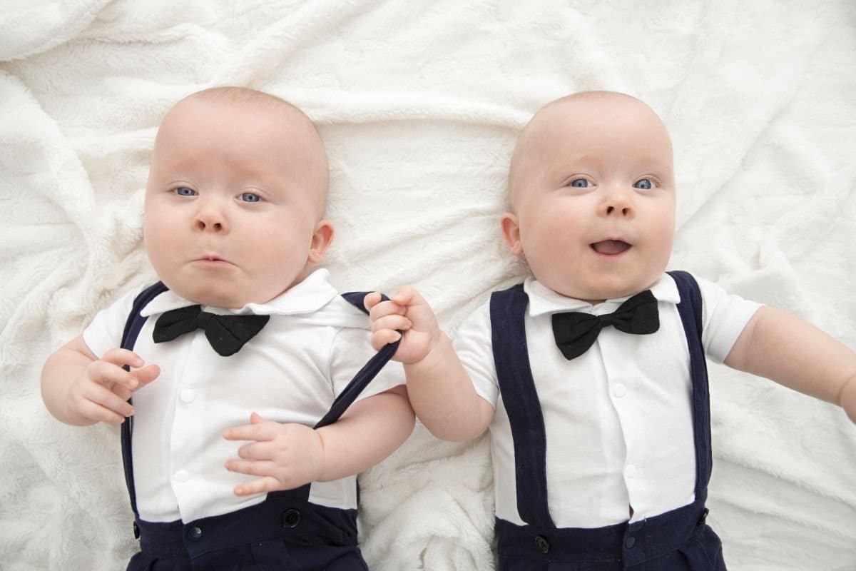 tweelingmoeder - tweeling baby's samen op bed met identieke pakjes en strikjes