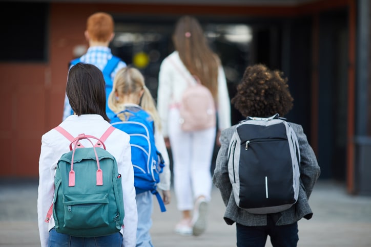 kinderen met rugzakken lopen school in - voorbereiden op de middelbare school