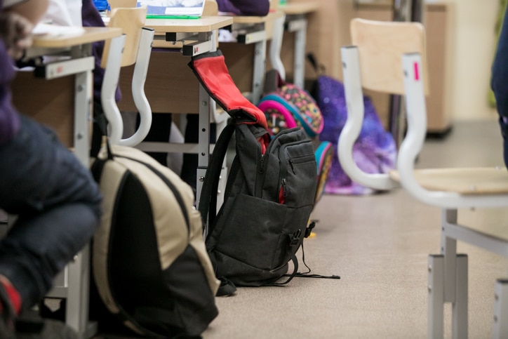 schooltassen naast tafels en lege stoelen in klas voorbereiden op de middelbare school