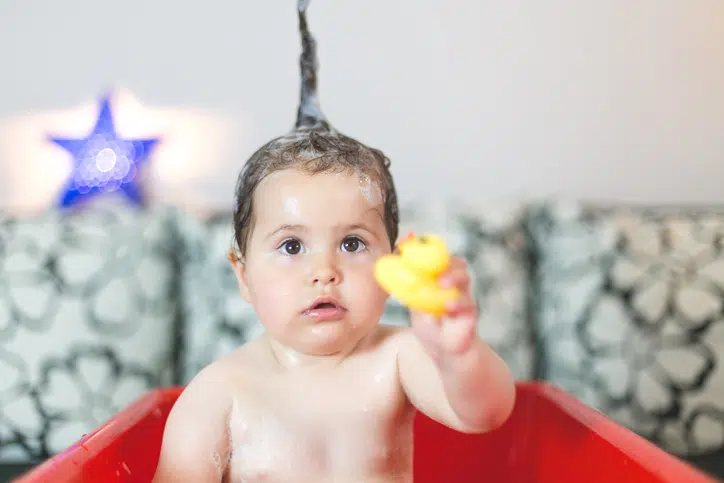 baby speelt met badeend in badje - spelen op de buik voor baby's