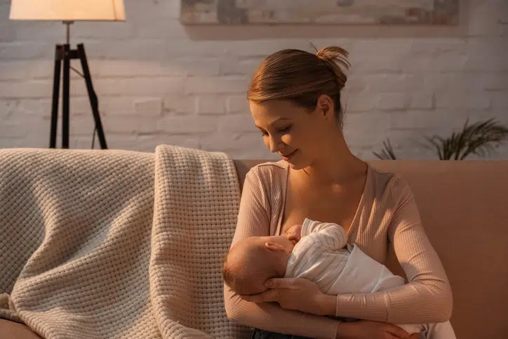 lanoline tepelcreme bij borstvoeding - vrouw geeft baby borstvoeding op de bank