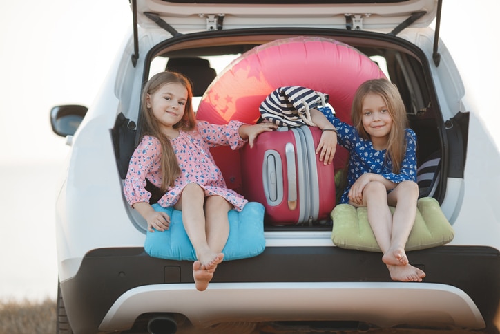 autovakantie met peuter - twee lachende meisjes met koffer in de auto