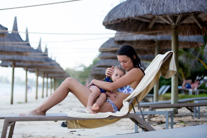 vrouw voedt kind op strandstoel - vrouwen stoppen te vroeg met borstvoeding