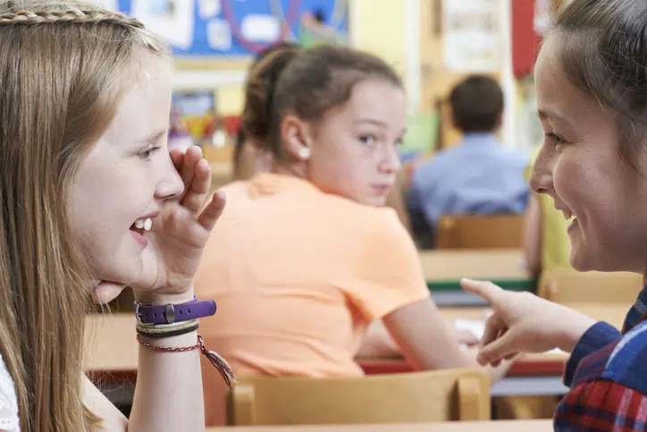als je kind een pester is - meisjes praten over een klasgenoot in de klas