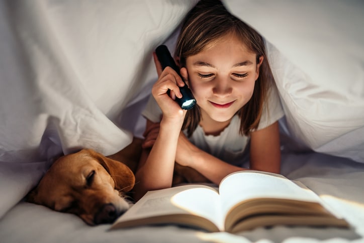 meisje leest boek onder de deken samen met hond - leescrisis