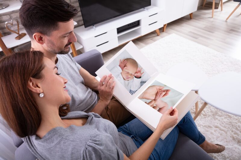 Vader en moeder kijken in fotoalbum van baby