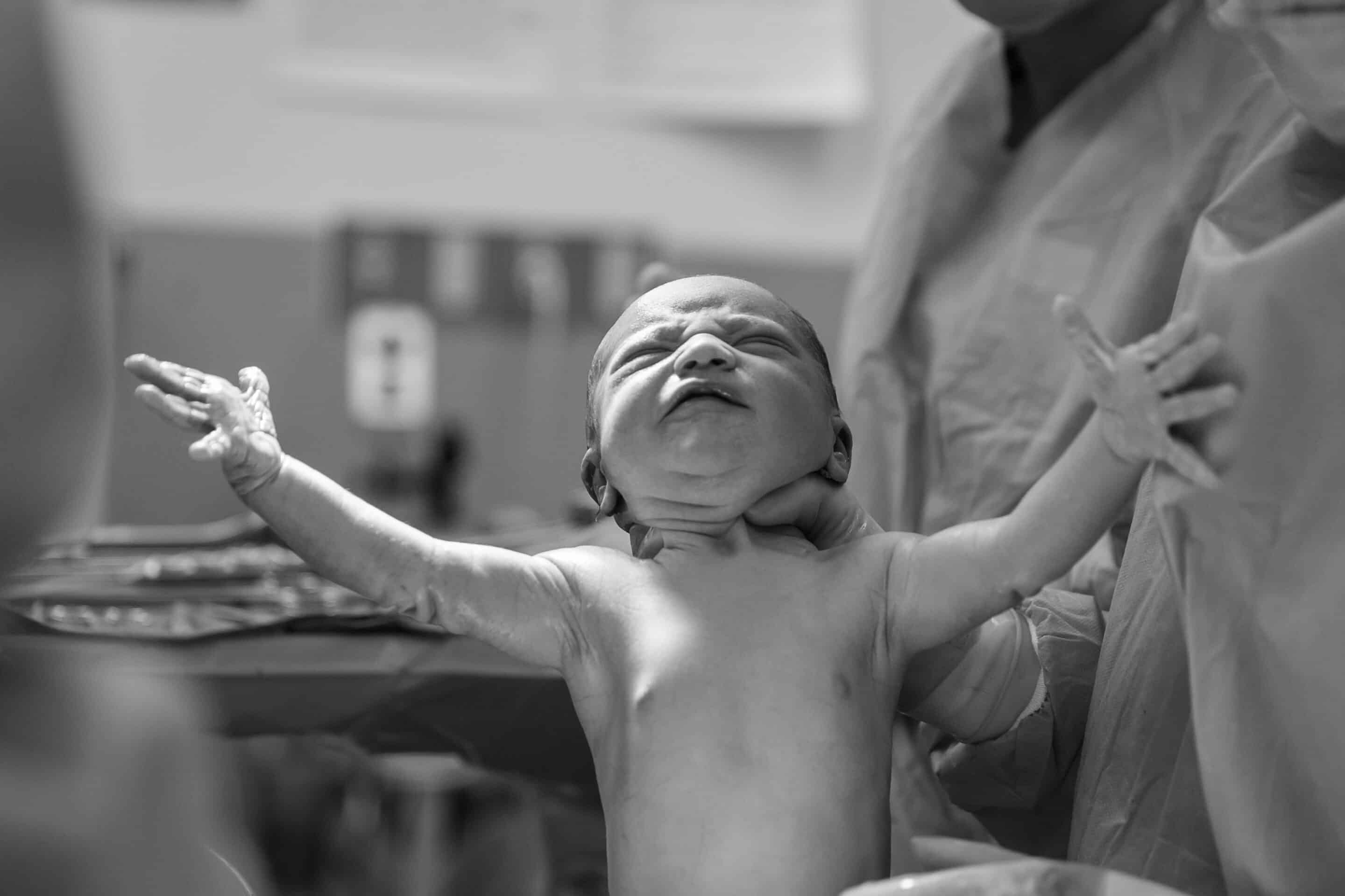 bevallingsfoto - pasgeboren baby huilt en spreidt armpjes
