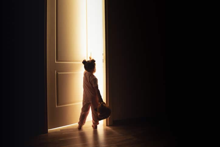 kind 's nachts wakker - meisje opent deur in het donker