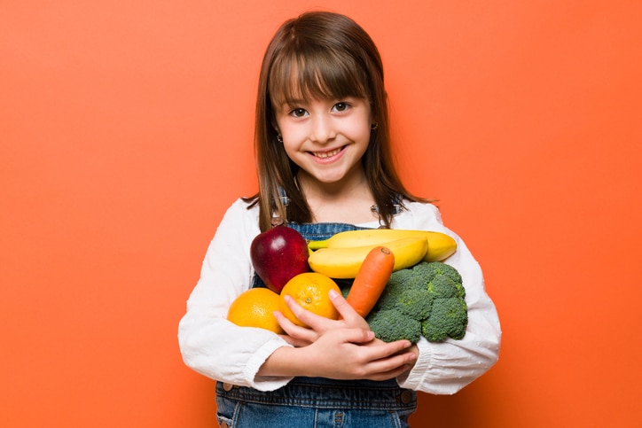 kind meer groente laten eten - meisje met armen vol groente