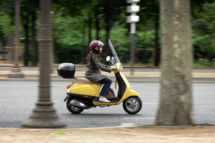 vrouw op scooter rijdt door park